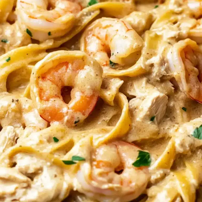 How to make a delicious chicken and shrimp Alfredo at home 11 A close-up of a creamy shrimp and chicken fettuccine Alfredo, coated in a rich, golden sauce with fresh herbs.
